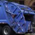 Garbage truck collecting trash on city street